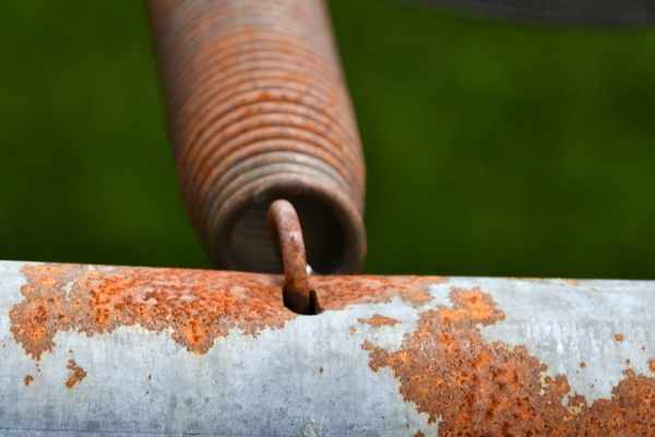 A rusted metal trampoline frame and spring.